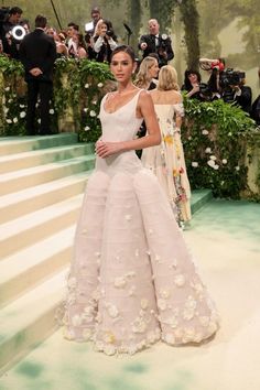 a model walks the runway in a white gown with floral appliques on it