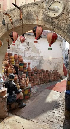 many pots and vases are on display under an archway