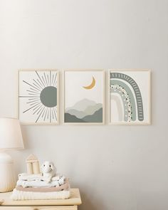 three framed pictures hang on the wall above a nightstand with a stuffed animal and blanket