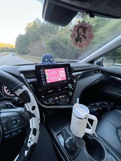 the interior of a car with steering wheel controls and dashboard, coffee cup on the dash