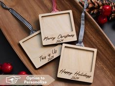 three personalized wooden christmas ornaments on a tray with ribbon and pine cones in the background