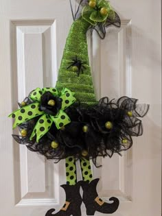 a door hanger decorated with green and black polka dots, a witch's hat and boots