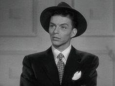 a man in a suit and hat with his arms crossed