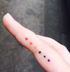 a person's left hand with small dots on the middle finger and one dot in the middle