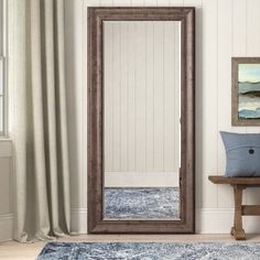 a large mirror sitting on top of a wooden floor next to a bench and window