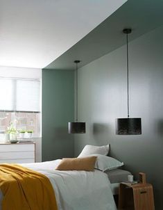 a bedroom with gray walls, white bedding and yellow throw blanket on the bed