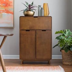 a wooden cabinet with two plants on top of it next to a chair and table