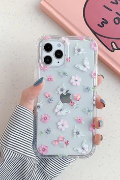 a woman is holding up her phone case with flowers on the front and back cover