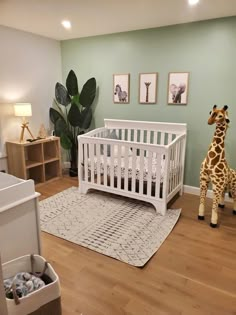 a baby's room with a giraffe stuffed animal next to the crib