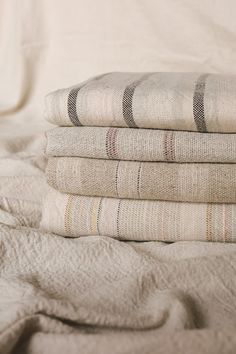 a stack of folded towels sitting on top of a bed next to a white blanket