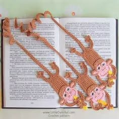 three crocheted monkeys are hanging from a book with two strings attached to it