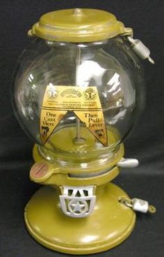 an old fashioned yellow gummy machine with glass bowl and plastic cover on the top