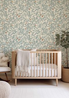 a baby's crib in front of a wallpapered with leaves and flowers