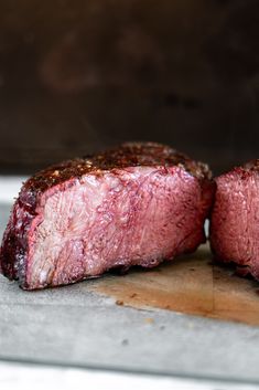 two pieces of steak sitting on top of a cutting board