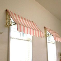 two windows with red and white awnings in a room next to each other