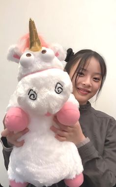 a woman holding a white stuffed unicorn with a gold horn