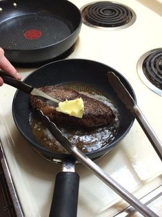 a person is cooking steak in a skillet on the stove with two spatulas