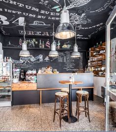 the interior of a restaurant with chalk writing on the wall and wooden stools in front