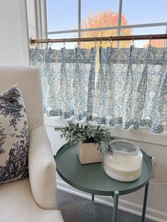 a small table with a potted plant on it next to a window sill