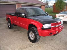 a red pick up truck parked in front of a garage