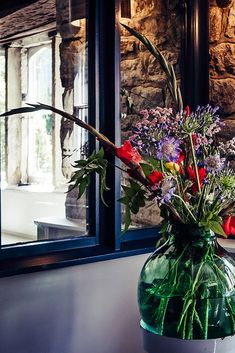 a vase filled with flowers sitting on top of a window sill next to a wall