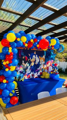 a balloon arch with sonic the hedgehog balloons on it in front of a picnic table