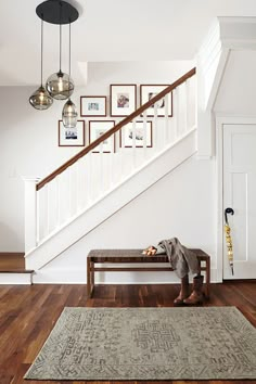 a person sitting on a bench in front of a stair case with pictures above it