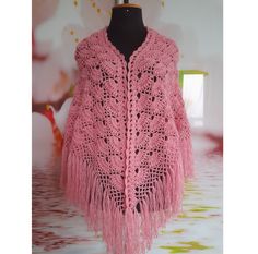 a pink crocheted shawl with tassels and fringed edges on a mannequin