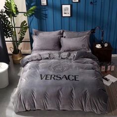 a bedroom with blue walls and a bed covered in grey sheets, pillows and blankets