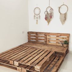 a bed made out of wooden pallets in a room with two hanging dream catchers on the wall