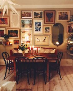 a dining room table with candles on it in front of many pictures and framed photos