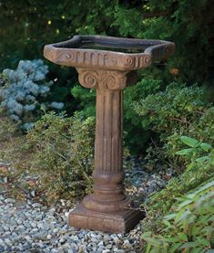 a bird bath sitting in the middle of some gravel