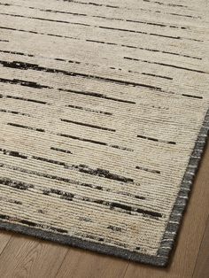 a beige and black area rug on a wooden floor with wood floors in the background