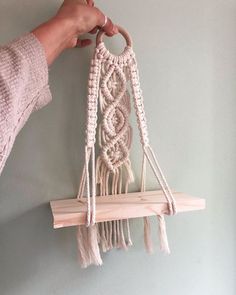 a person is holding a macrame hanging on a wall