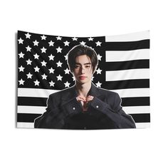 the young man is standing in front of an american flag with his hands folded up