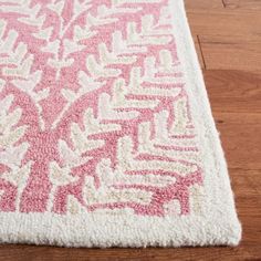 a pink and white rug on top of a wooden floor