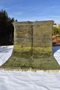 a blanket is laying in the snow on top of a table cloth with fringes