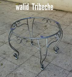 a metal table sitting on top of a tiled floor next to a sidewalk with the words walid tribeche written above it