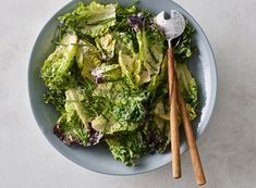 a bowl filled with lettuce and two wooden spoons on top of it