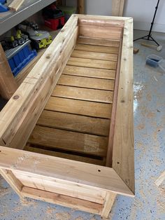 a wooden bench sitting inside of a room on top of a hard wood floor next to a workbench