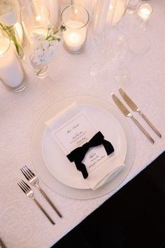 a white table with silverware and candles