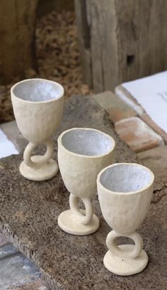 three white cups sitting on top of a stone slab