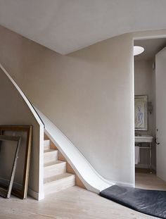 an empty room with stairs leading up to the second floor and a painting on the wall