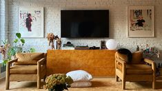 a living room with two chairs and a flat screen tv mounted on the wall above it