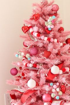 a pink christmas tree decorated with hearts and ornaments