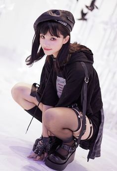 a woman kneeling on the ground with her legs crossed and wearing high heeled boots