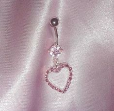 a heart shaped belly ring with pink crystals on it's side and a dangling ball