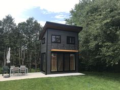 a small black house sitting on top of a lush green field