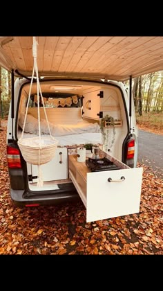 a camper van is parked in the woods with its bed pulled up to it's side