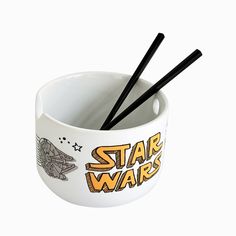 two black chopsticks in a white bowl with star wars design on the side